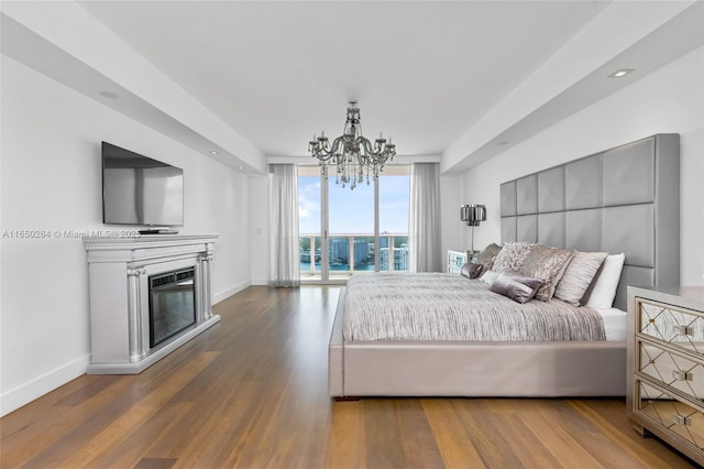 bedroom featuring hardwood / wood-style floors, access to outside, expansive windows, and a notable chandelier