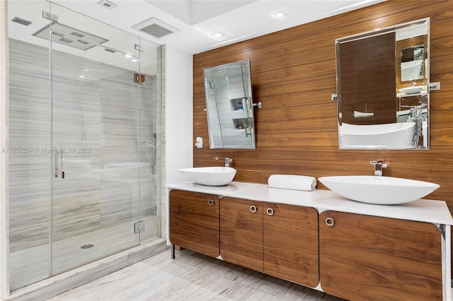 bathroom with vanity, a shower with shower door, and wooden walls