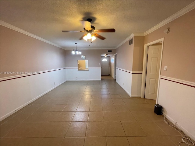 empty room with a textured ceiling, ornamental molding, ceiling fan with notable chandelier, and tile patterned flooring