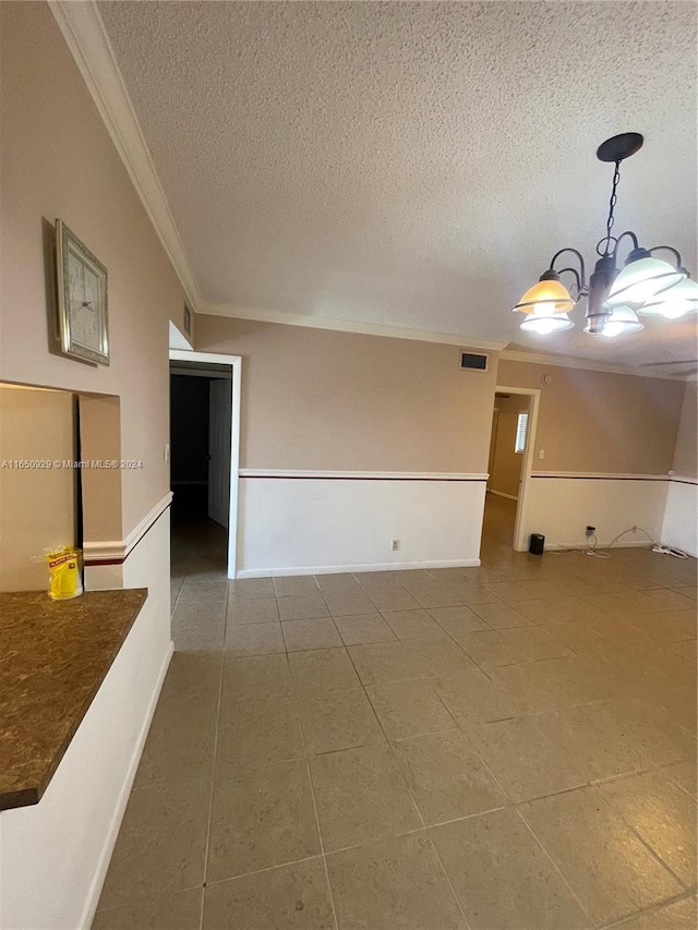 spare room with a textured ceiling, ornamental molding, and tile patterned floors