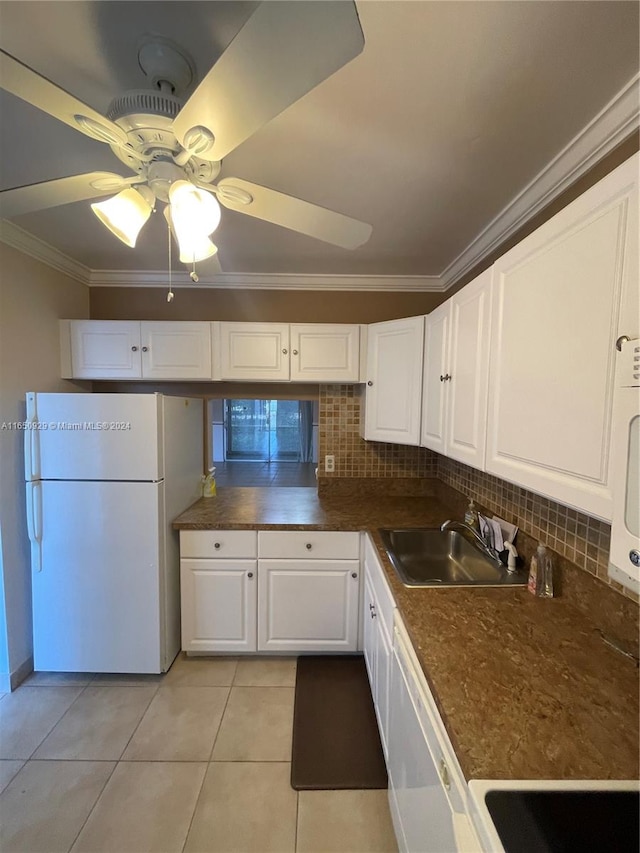 kitchen featuring white appliances, tasteful backsplash, sink, ceiling fan, and white cabinets