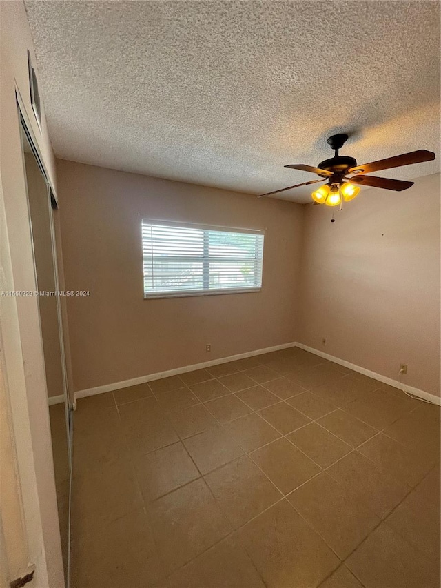 tiled empty room featuring a textured ceiling and ceiling fan