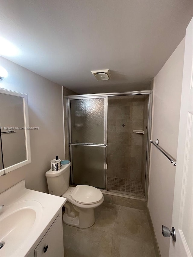 bathroom featuring vanity, a shower with shower door, and toilet