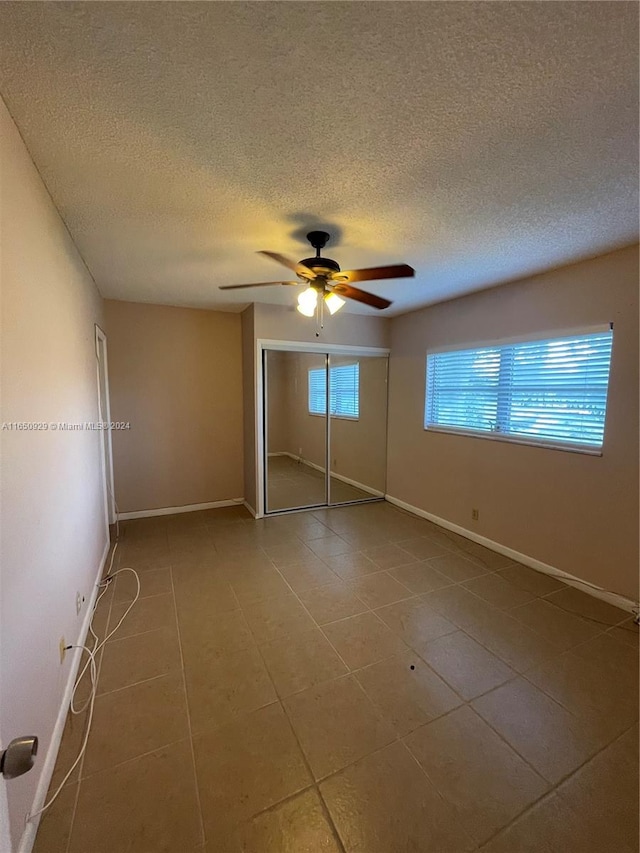 unfurnished bedroom featuring tile patterned flooring, a closet, ceiling fan, and a textured ceiling