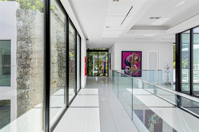 corridor with light tile patterned flooring and a wall of windows