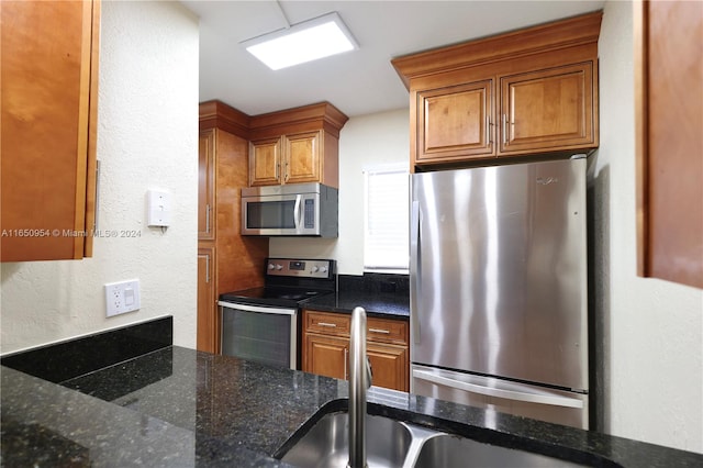 kitchen with appliances with stainless steel finishes, sink, and dark stone counters