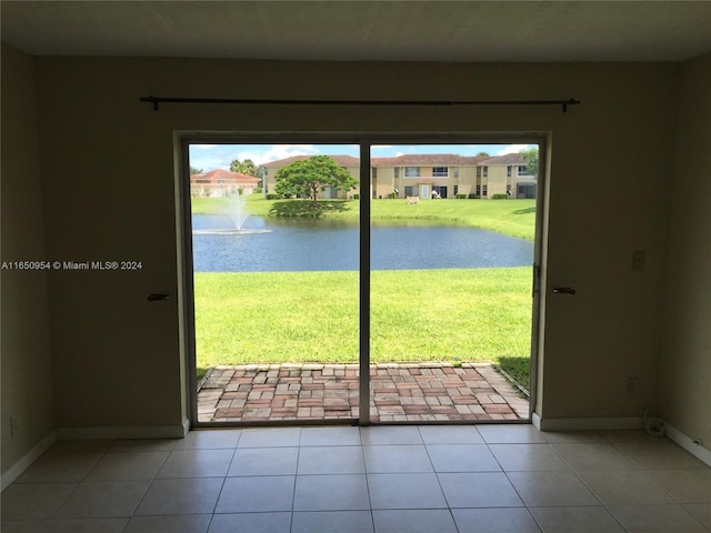 doorway to outside featuring tile patterned floors, baseboards, and a water view