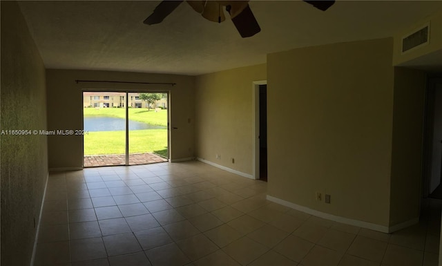 unfurnished room featuring light tile patterned floors, a ceiling fan, baseboards, visible vents, and a water view