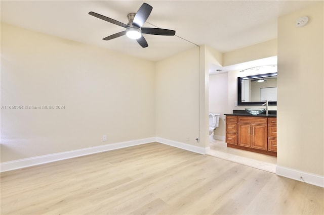 unfurnished bedroom featuring light wood-style flooring, ceiling fan, baseboards, and a sink
