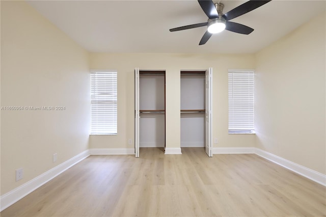 unfurnished bedroom with ceiling fan, multiple closets, and light hardwood / wood-style flooring