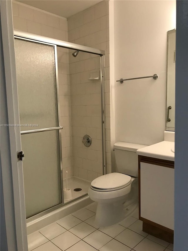 bathroom with tile patterned flooring, walk in shower, toilet, and vanity