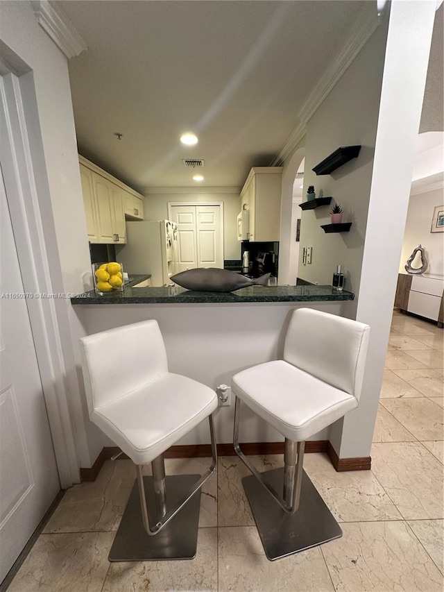 kitchen with a kitchen breakfast bar, kitchen peninsula, white appliances, and ornamental molding