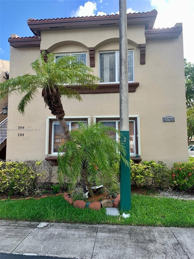 view of side of home featuring stucco siding and a tile roof