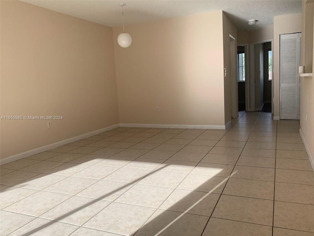 unfurnished room featuring light tile patterned floors, baseboards, and a textured ceiling