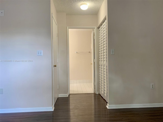 hall featuring wood finished floors, baseboards, and a textured ceiling