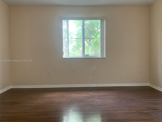 spare room featuring dark wood finished floors and baseboards