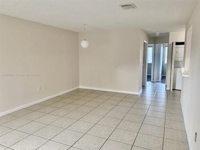 empty room featuring light tile patterned floors, visible vents, a textured ceiling, and baseboards