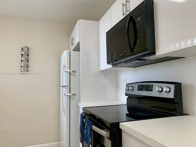 kitchen featuring electric range, a textured ceiling, freestanding refrigerator, white cabinets, and black microwave