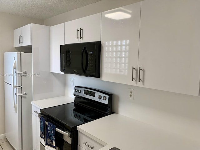 kitchen featuring stainless steel electric range oven, light countertops, black microwave, and freestanding refrigerator