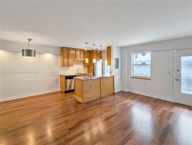 kitchen with kitchen peninsula, wood-type flooring, pendant lighting, and appliances with stainless steel finishes