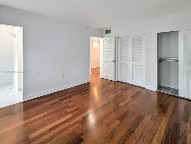 unfurnished bedroom featuring wood-type flooring and multiple closets