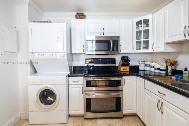 kitchen with stacked washer and clothes dryer, stainless steel appliances, and white cabinets