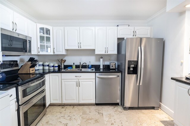 kitchen featuring dark stone countertops, crown molding, stainless steel appliances, sink, and white cabinets