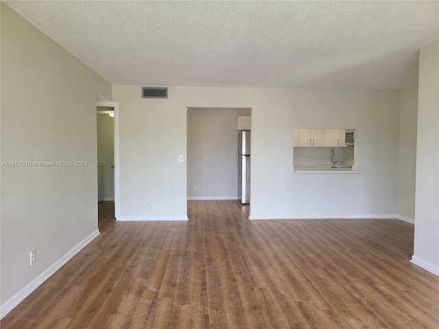 unfurnished room with dark wood-type flooring, a textured ceiling, and sink