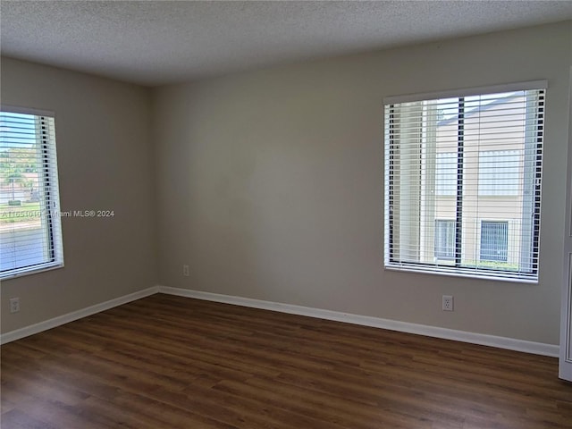 empty room with dark wood-type flooring and a textured ceiling