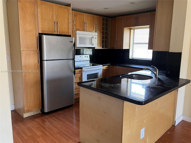 kitchen with white appliances, hardwood / wood-style flooring, kitchen peninsula, and sink