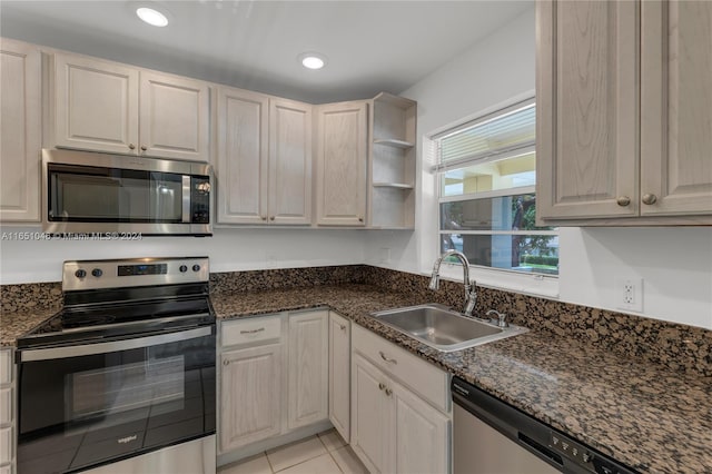 kitchen featuring light tile patterned flooring, dark stone countertops, stainless steel appliances, and sink