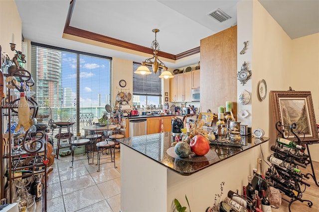 kitchen featuring ornamental molding, decorative light fixtures, kitchen peninsula, a tray ceiling, and appliances with stainless steel finishes