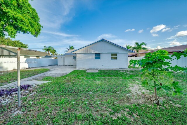 rear view of house with a fenced backyard, a lawn, and a patio