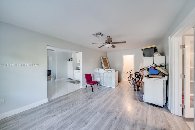 interior space featuring light wood-type flooring, white appliances, washing machine and dryer, and ceiling fan