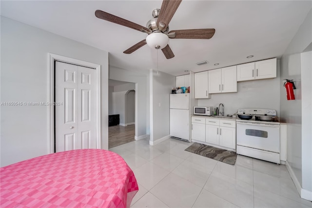 kitchen featuring white appliances, light tile patterned floors, sink, ceiling fan, and white cabinets