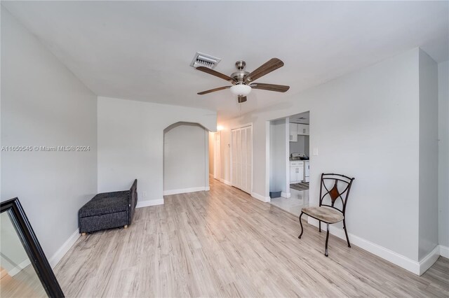 sitting room featuring baseboards, arched walkways, visible vents, ceiling fan, and wood finished floors