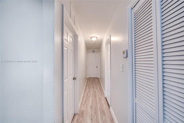 hall featuring light wood-type flooring, visible vents, and baseboards