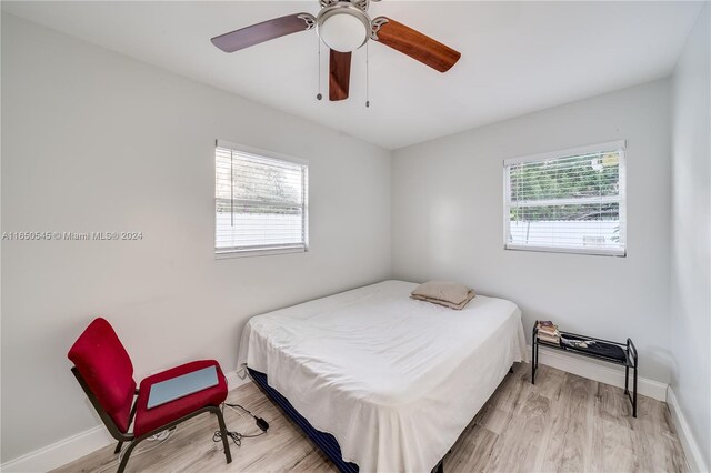 bedroom with a ceiling fan, multiple windows, light wood-style flooring, and baseboards