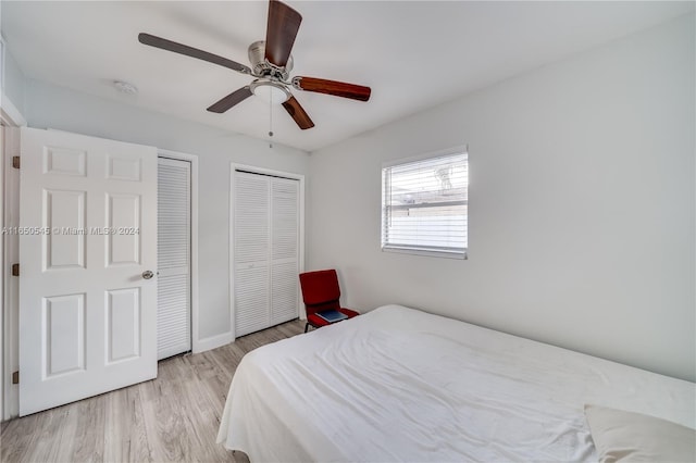 bedroom featuring multiple closets, light hardwood / wood-style flooring, and ceiling fan