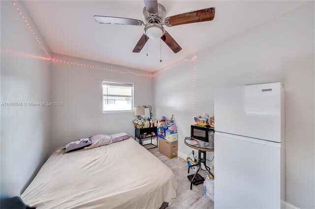 bedroom featuring ceiling fan, light wood-style flooring, and freestanding refrigerator