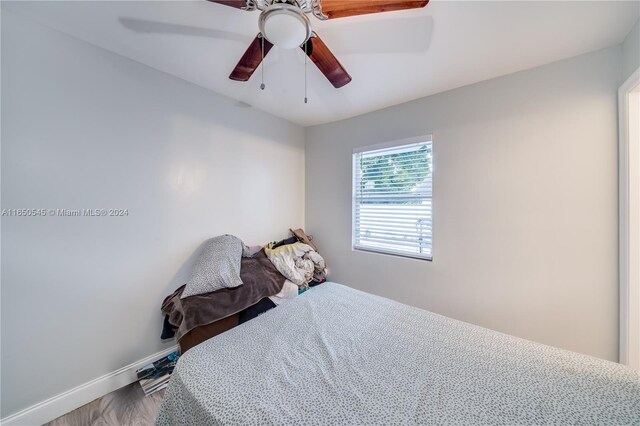 bedroom featuring a ceiling fan, baseboards, and wood finished floors