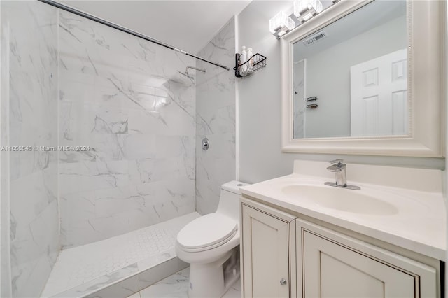 bathroom with toilet, a tile shower, and vanity