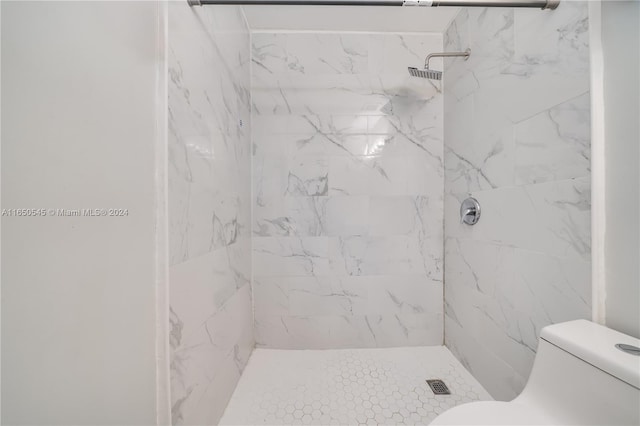 bathroom featuring tiled shower and toilet