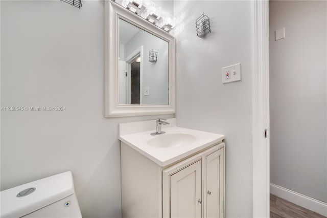 bathroom with vanity, toilet, and hardwood / wood-style floors