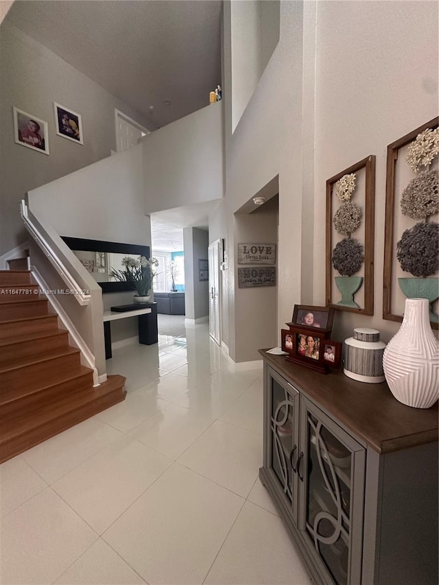 hall with a towering ceiling and light tile patterned floors