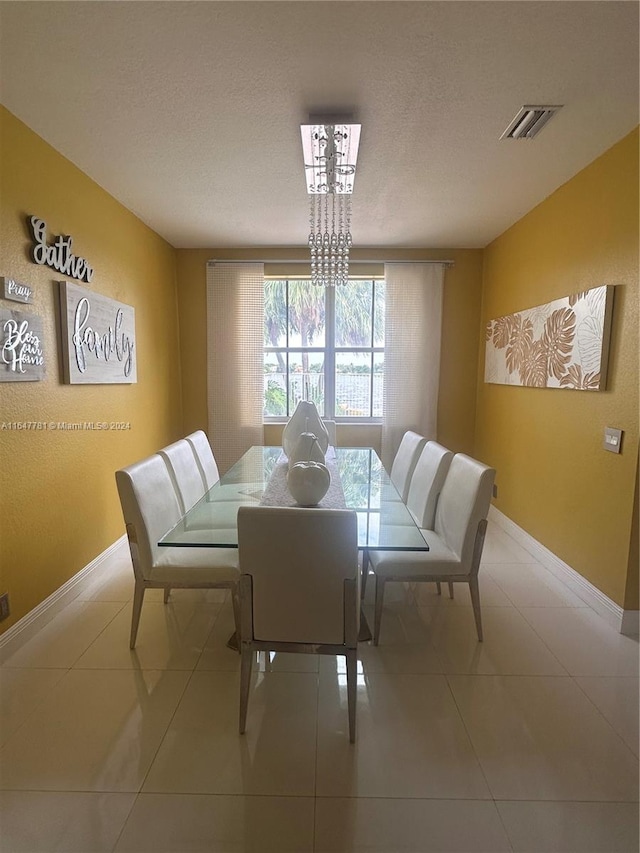 dining area with a chandelier, a textured ceiling, and tile patterned floors