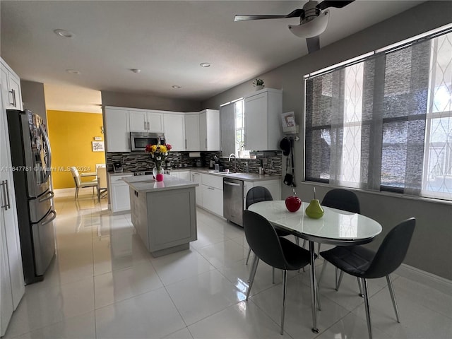 kitchen with white cabinets, appliances with stainless steel finishes, a kitchen island, and ceiling fan