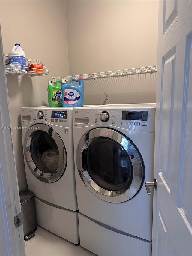 washroom with light tile patterned floors and washing machine and clothes dryer