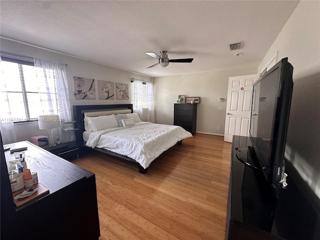 bedroom featuring ceiling fan, a textured ceiling, and light hardwood / wood-style flooring