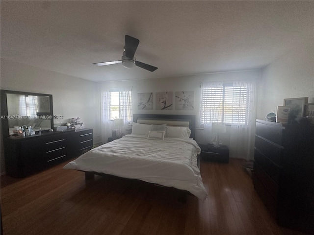 bedroom with ceiling fan, dark hardwood / wood-style flooring, and a textured ceiling